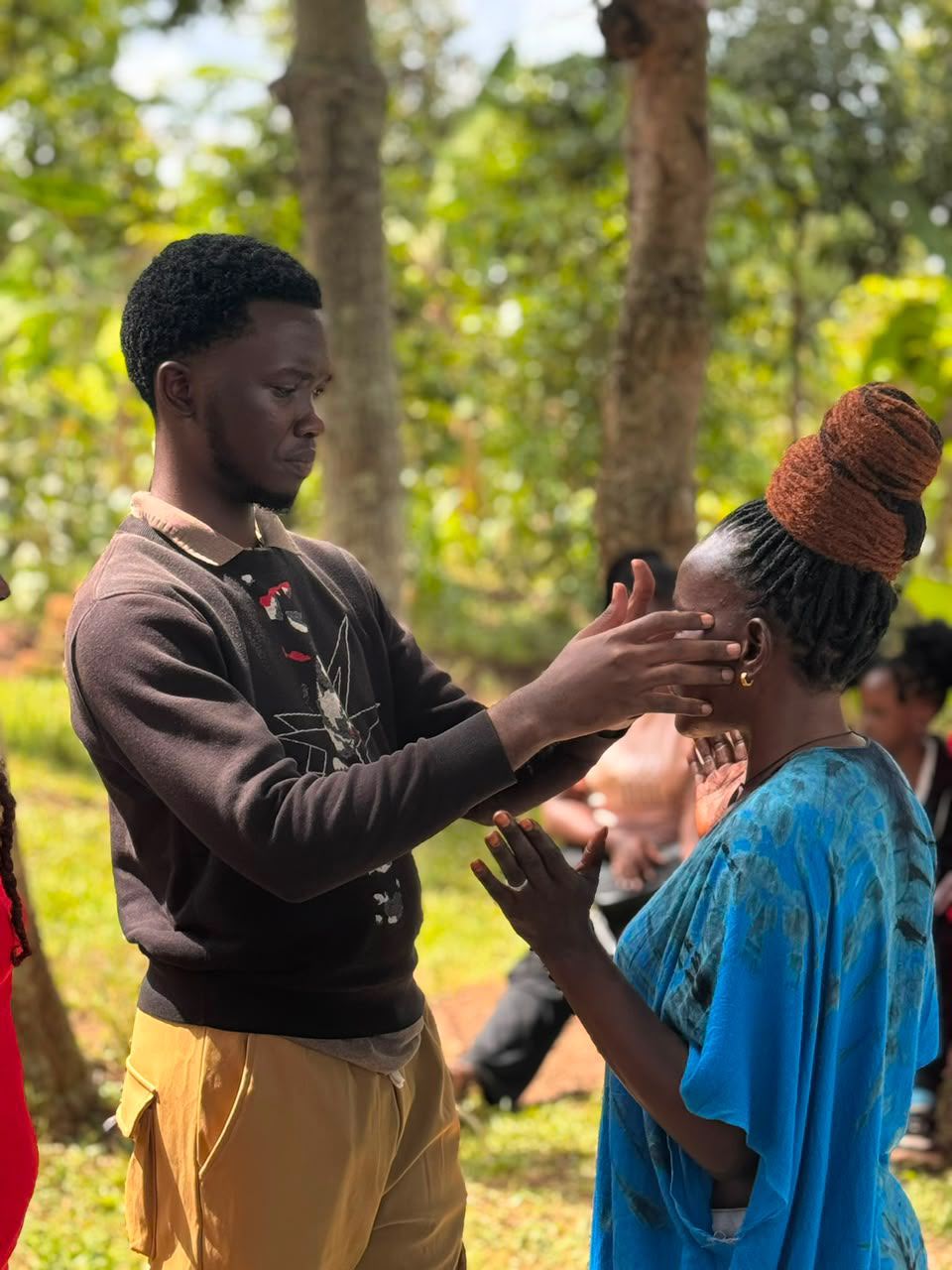 Prophet Abbey praying over a woman in the open field